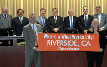Mayor Rusty Bailey and Chief Innovation Officer Lea Deesing in frontground; Riverside City Council with What Works Cities banner